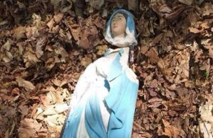 zniszczona zabytkowa figurka Matki Boskiej leży w liściach