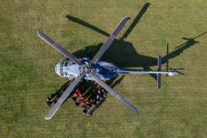 Śmigłowiec Black Hawk na trawiastym lądowisku widziany z góry.