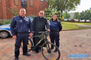 policjant i policjantka oraz ksiądz z odzyskanym rowerem