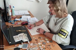 Policjantka siedzi przed laptopem i ma rozłożone na stole dokumenty