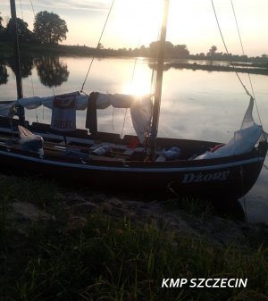 Zwodowana łódź masztowa, w tle zachód słońca