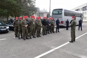 grupa żołnierzy żandarmerii wojskowej stojąca w trzech szeregach, za nimi stoi autokar w kolorze szarym