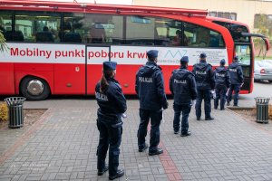 Policjanci stojący w kolejce przed krwiobusem