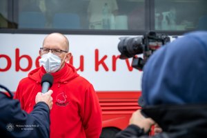 Jarosław Zwierzyński, kierownik działu pobrań w RCKiK w Olsztynie udziela wywiadu, w tle krwiobus