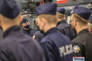 na pierwszym planie rozmyte plecy policjantów, w tle Komendant Głowny Policji