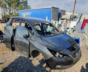 miejsce ujawnienia przez policjantów podzespołów samochodowych pochodzących z kradzieży, na pierwszym planie częściowo zdekompletowany elektryczny nissan leaf