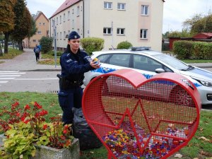 umundurowana policjantka wrzuca nakrętki do ustawionego serca. w tle widać policyjny radiowóz