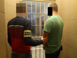 Na zdjęciu widoczny nieumundurowany policjant wraz z zatrzymanym mężczyzną