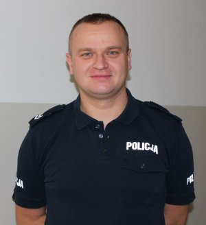 policjant w koszulce z napisem Policja pozuje do zdjęcia