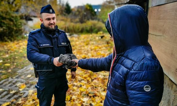 umundurowany policjant przekazuje mężczyźnie czapkę