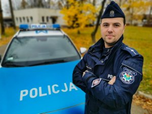 umundurowany policjant stoi przed radiowozem