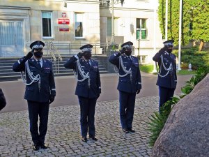 Komendant Główny Policji wraz z zastępcami oddaje honor przez obeliskiem &quot;Poległym Policjantom - Rzeczpospolita Polska&quot; na dziedzińcu KGP. W tle budynek komendy.