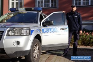 umundurowany policjant stoi przy radiowozie