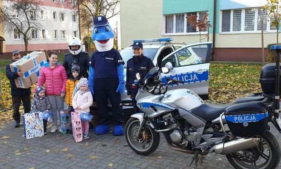 Pamiątkowe zdjęcie Kubusia, jego rodziny i policyjnych przyjaciół. Z prawej strony widoczny jest policyjny motocykl a z tyłu radiowóz