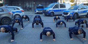 Policjanci w mundurach robią pompki na placu apelowym