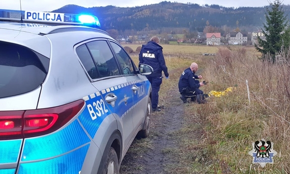 policjanci przy radiowozie owijający kobietę kocem termicznym