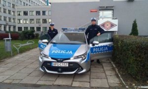 dwaj policjanci stoją obok radiowozu