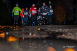 pora nocna, mężczyźni i kobiety w strojach sportowych w trakcie biegu