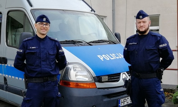 dwaj policjanci stoją przy radiowozie