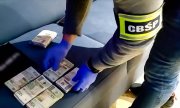 policjant zabezpiecza pliki banknotów