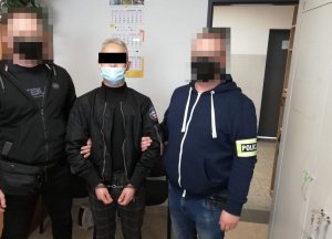 dwóch policjantów stoi z zatrzymanym mężczyzną