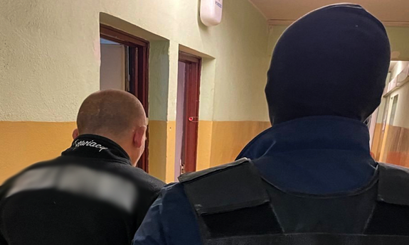 policjant w kominiarce z zatrzymanym mężczyzną