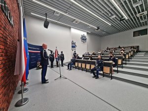 Sala Konferencyjna Komendy Głównej Policji - po lewej Komendant Główny Policji przemawia do mikrofonu, w tle siedzą w rzędach wyróżnieni pracownicy