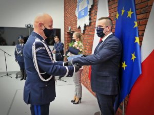 Komendant Główny Policji (z lewej) wręcza list gratulacyjny wyróżnionemu pracownikowi