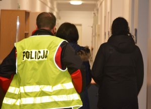 dwaj policjanci prowadzą zatrzymaną osobę