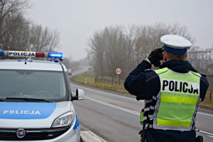 Droga, radiowóz, policjant z tyłu, obserwujący przez lornetkę