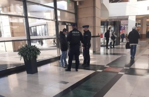 dwaj policjanci kontrolują mężczyznę, wnętrze galerii handlowej w tle ludzie