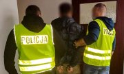 policjanci ubrani w żółte kamizelki z napisem Policja prowadzą zatrzymanego mężczyznę