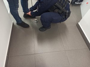 policjant zakłada kajdanki na kostki podejrzanemu