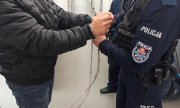 policjant zakłada kajdanki na ręce podejrzanemu