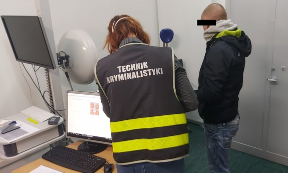 technik kryminalistyki z podejrzanym podczas daktyloskopii