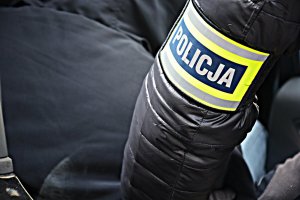 Ręka policjanta ubranego po cywilnemu z opaską POLICJA