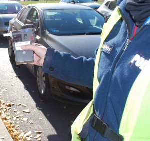 Na zdjęciu policjant trzymający w dłoni urządzenie do sprawdzania stanu trzeźwości