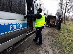 Na drodze stoi radiowóz, bus ,a przy autach stoją policjanci