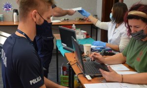 policjant siedzi przed kobieta która ma przed sobą komputer i formularze