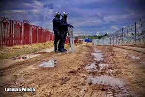 dwóch policjantów w umundurowaniu szturmowym na granicy&quot;&gt;