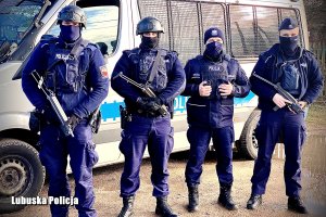 czterech policjantów Samodzielnego Pododdziału Prewencji Policji z długą bronią na tle radiowozu&quot;&gt;