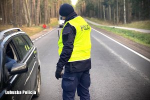 policjant w żółtej kamizelce z napisem Policja przy kontrolowanym pojeździe