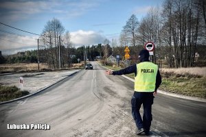 policjant w żółtej kamizelce z napisem Policja zatrzymuje nadjeżdżający pojazd