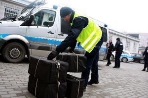 Policjanci stoją przy paczkach, za nimi stoi radiowóz