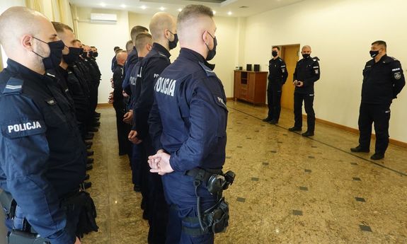 trzej oficerowie Policji stoją na przeciwko funkcjonariuszy oddziałów prewencji