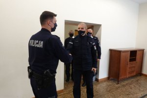 oficer Policji ściska dłoń policjantowi. Za Zastępca Komendanta Głównego idą dwaj oficerowie