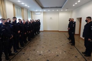 trzej oficerowie Policji stoją na przeciwko funkcjonariuszy oddziałów prewencji