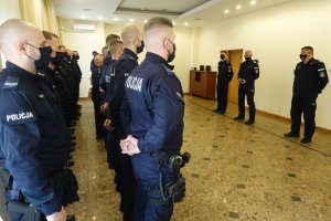 trzej oficerowie Policji stoją na przeciwko funkcjonariuszy oddziałów prewencji