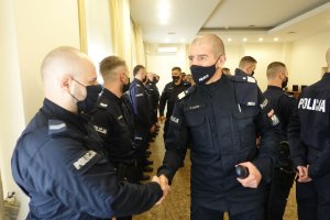 umundurowany oficer Policji ściska dłoń jednemu z funkcjonariuszy oddziałów prewencji, którzy stoją w dwuszeregu