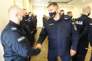 umundurowany oficer Policji ściska dłoń jednemu z funkcjonariuszy oddziałów prewencji, którzy stoją w dwuszeregu